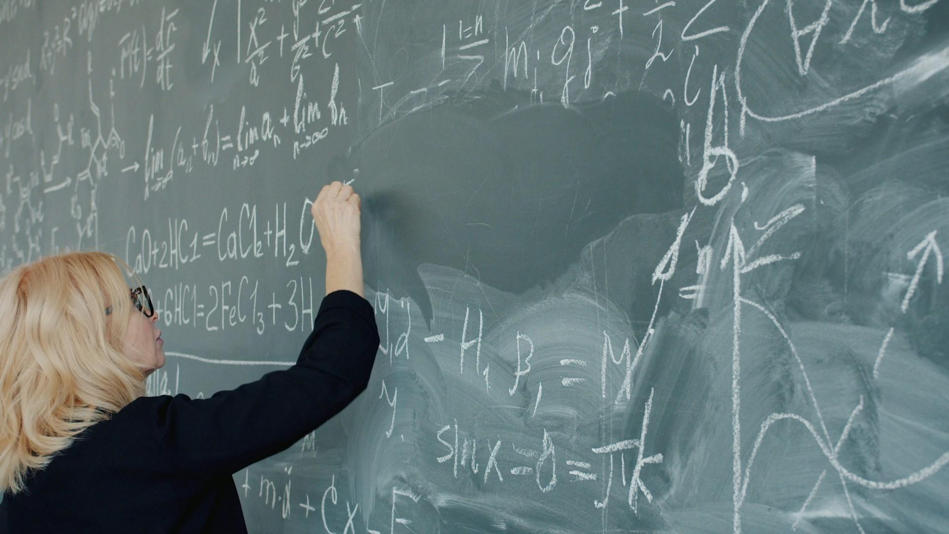 A teacher writing on a blackboard